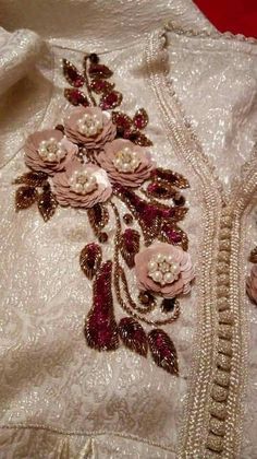 an embroidered jacket with flowers and pearls on the front, sitting on a red surface