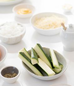 there are many bowls with food in them on the table, including cucumbers and eggs