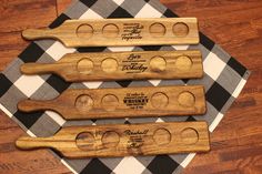 three wooden utensils with engraved names on them sitting on a checkered tablecloth