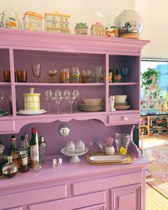 a purple china cabinet filled with dishes and wine glasses on top of it's shelves