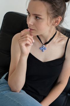 a woman sitting in a chair with her hand on her chin and wearing a necklace