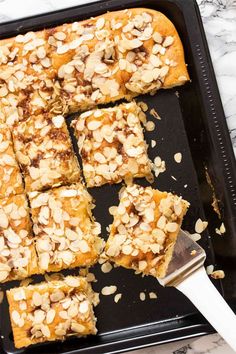 sliced almond bars sitting on top of a black tray next to a white knife and fork