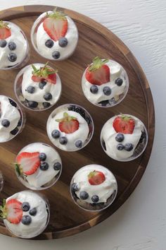 cupcakes with strawberries and blueberries in them on a wooden platter