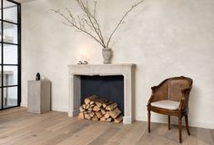 a room with a fireplace, chair and vase on top of the mantel in front of it