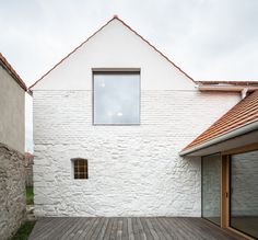 the house is made out of white bricks and has an open window on one side