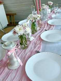 the table is set with white plates and pink napkins