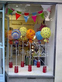 there is a display in the window with many balloons and candles on sticks that say happy birthday