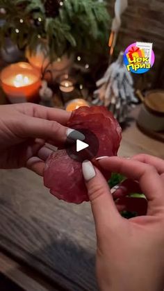 two hands holding pieces of raw meat in front of a table with candles and christmas decorations