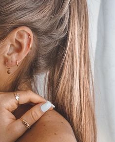 a close up of a person wearing gold ear rings and an earring on her left ear