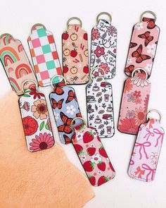 six different colored luggage tags with flowers and butterflies on them, one has a keychain attached to it