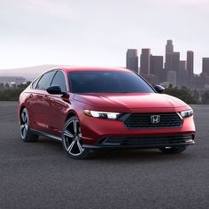 a red car parked in front of a city skyline