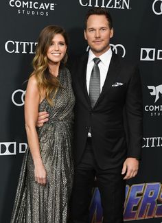 a man in a suit and tie standing next to a woman on a red carpet