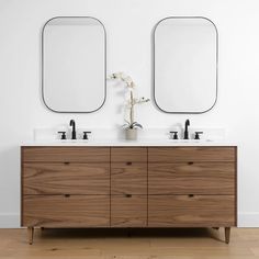 two mirrors are above the double sink vanity in this white bathroom with wood flooring