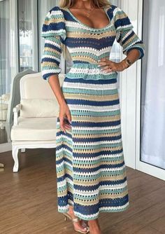 a woman standing in front of a window wearing a blue and white striped crochet dress