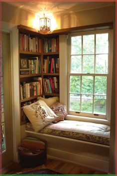 a window seat in front of a bookshelf filled with lots of books and pillows