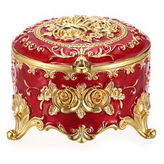 a red and gold box with ornate designs on the lid, sitting on a white surface