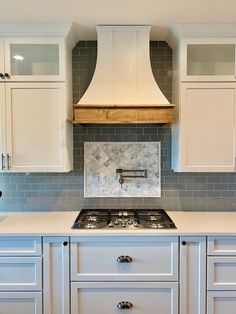 a stove top oven sitting inside of a kitchen next to white cupboards and drawers