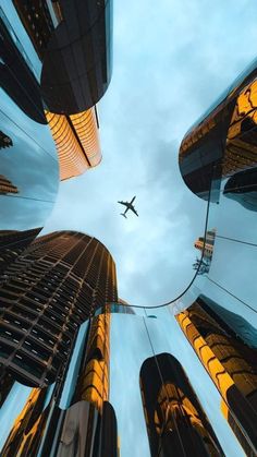 an airplane is flying through the sky between tall buildings