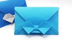 an origami envelope with a bow on the front, and one folded in blue paper