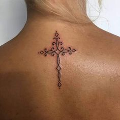 a cross tattoo on the back of a woman's neck, with an intricate design