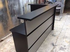 a black reception desk sitting on top of a brick floor next to a metal wall