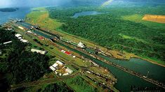 an aerial view of a river and green land with a rainbow in the sky above