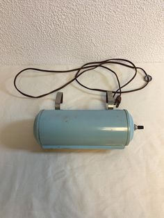 a small blue object is sitting on a white sheet with a cord attached to it