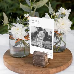 two mason jars with flowers in them are on a wooden stand next to a card that says tame no