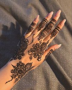 a woman's hand with henna tattoos on it