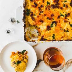 a casserole dish on a plate with a glass of tea next to it