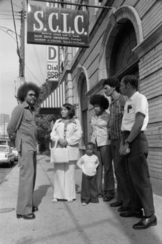 black and white photograph of people standing in front of a building with a sign that says sclcc