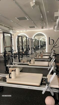 a gym with rows of exercise equipment and mirrors on the wall, all in white