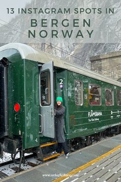 a person standing next to a green train on the tracks with snow all over it