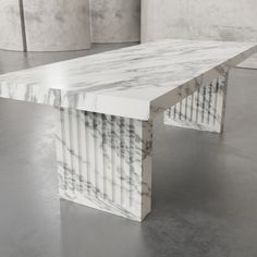 a white marble table sitting on top of a floor next to two wall panels in the background