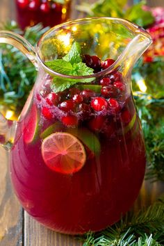 a pitcher filled with cranberry punch and garnished with fresh greenery