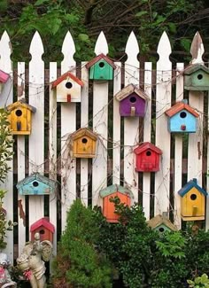 a white picket fence with colorful bird houses on it