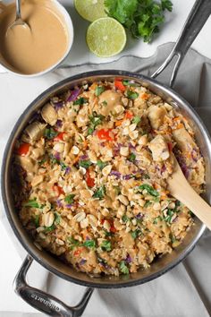 a pan filled with rice and vegetables next to some dipping sauces on the side