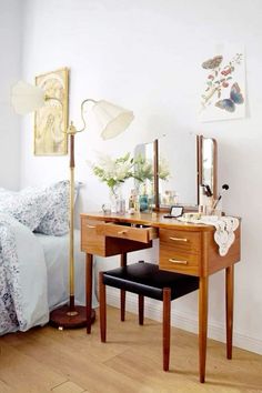 a bedroom with a bed, desk and mirror on it's side table next to a lamp