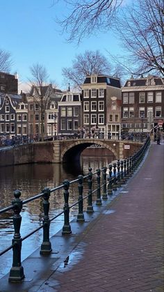 a bridge that is over some water with buildings in the background and people walking on it