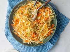 a bowl filled with shredded carrots on top of a blue and white towel next to a spoon