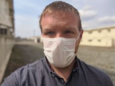 a man wearing a face mask in front of a building with no people on it