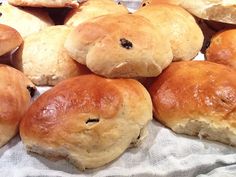 several rolls with raisins on them sitting on top of a white table cloth