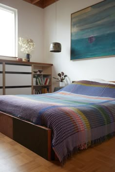 a bed sitting in a bedroom next to a dresser and book shelf on top of a hard wood floor