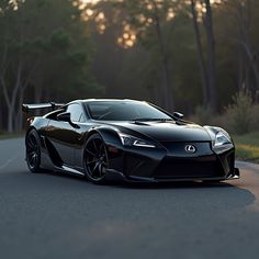 a black sports car driving down the road in front of some trees and bushes at sunset