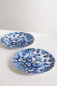 two blue and white plates sitting on top of a table next to eachother