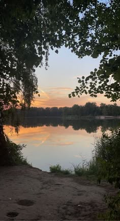 the sun is setting over a calm lake