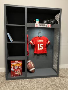 a football jersey and helmet are on display in a locker with books, magazines, and other sports memorabilia