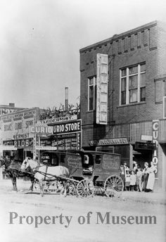 an old black and white photo of people standing in front of a building with horses pulling carriages