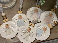 four plates with angel ornaments on them sitting on a table next to other items and decorations