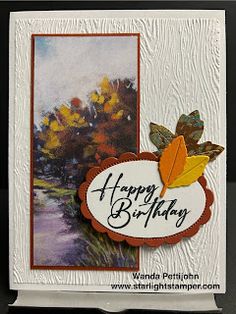 a happy birthday card with an autumn scene and leaves on the front, sitting on a table